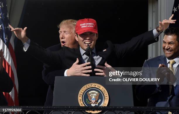 President Donald Trump reacts as player Kurt Suzuki wears a "Make America Great Again" baseball hat during a ceremony to welcome the 2019 World...