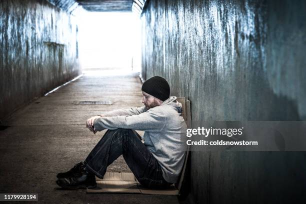 obdachloser junger mann sitzt in kaltem u-bahn-tunnel - landstreicher stock-fotos und bilder