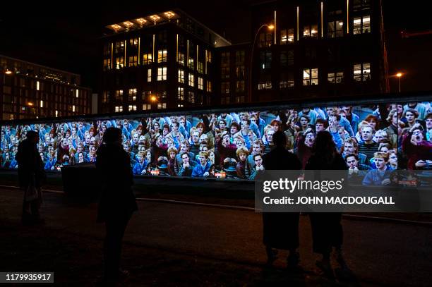 Footage showing mass demonstrations in the former east Germany is projected on a stretch of the Berlin wall at the so-called East-side Gallery during...