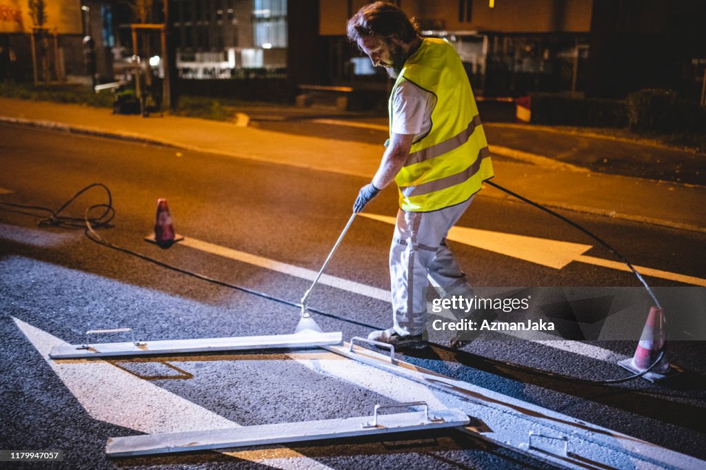 Transportation Worker Repainting Road Surface Marking