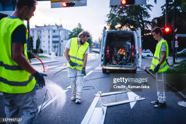 construction crew mitglied spray malerei turn arrow bei dämmerung - straßenmarkierung stock-fotos und bilder