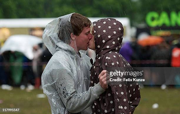 Couple kisses during heavy rainfall on day three of Roskilde Festival 2011 on July 2, 2011 in Roskilde, Denmark.