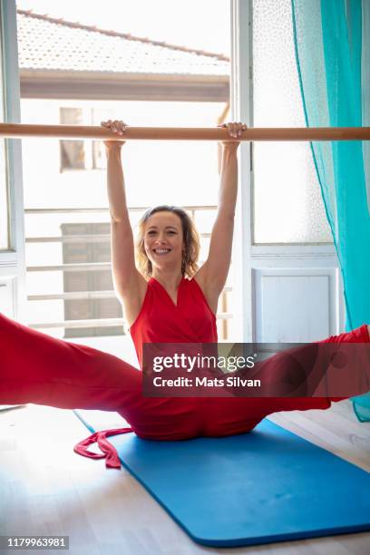 woman exercising pilates on mat with legs apart and arms in the air - mats silvan stock pictures, royalty-free photos & images