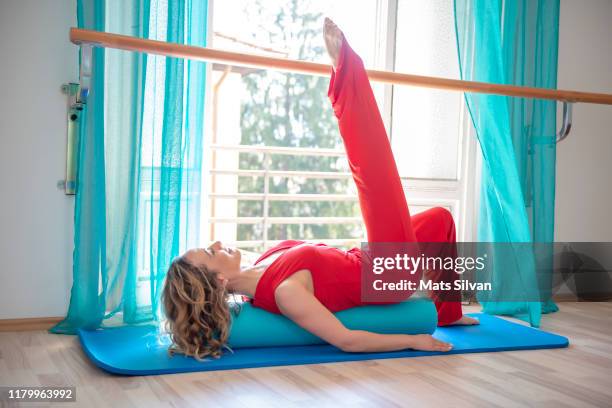 woman exercising pilates on mat with leg in the air - mats silvan stock pictures, royalty-free photos & images