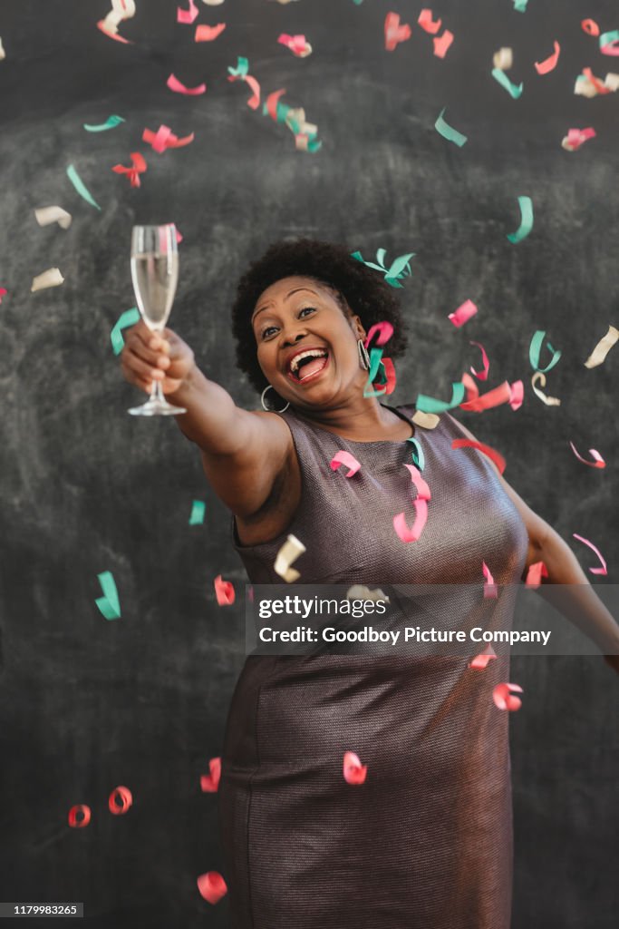 Confetti falling on a laughing African American woman with champagne