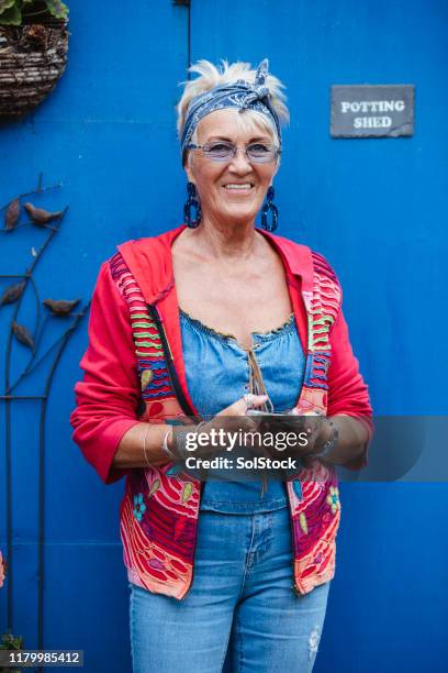 hipster senior woman outside her potting shed - eccentric woman stock pictures, royalty-free photos & images