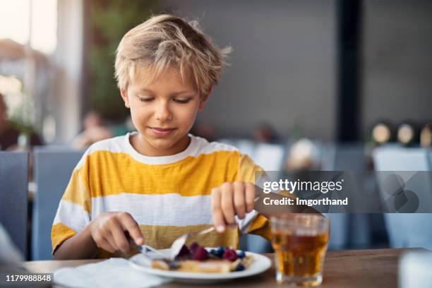 kleiner junge essen frühstück crepes mit früchten - eierkuchen speise stock-fotos und bilder