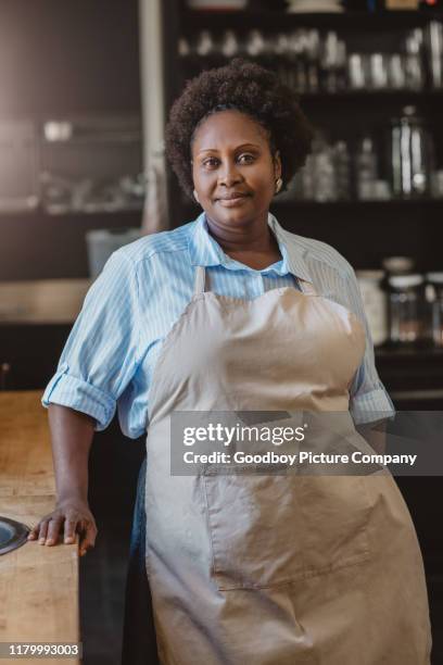 smiling african american woman standing at home in her kitchen - chef apron stock pictures, royalty-free photos & images
