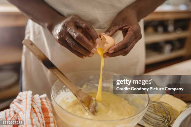 african american woman cracking eggs into a bowl of batter - crack spoon stock pictures, royalty-free photos & images