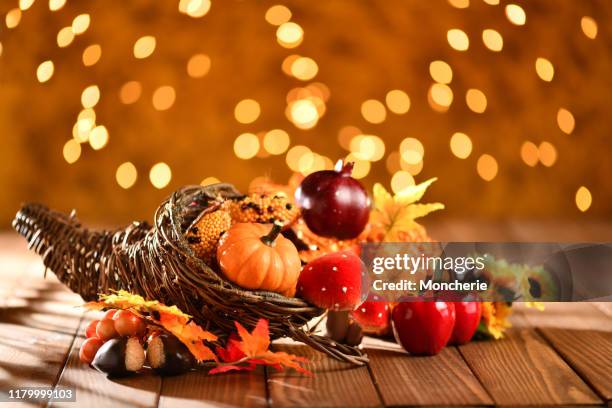 thanksgiving still life with cornucopia pumpkins and illuminated background on a rustic wooden table - cornucopia stock pictures, royalty-free photos & images