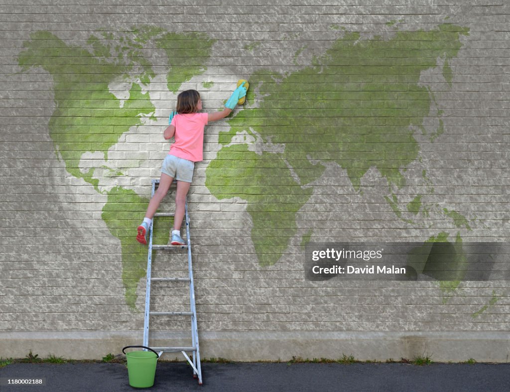A young girl on a ladder, who has started cleaning a world map mural.