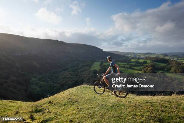 a mountain biker pausing to take in the view from the llangattock escarpment. - brecon beacons stock-fotos und bilder