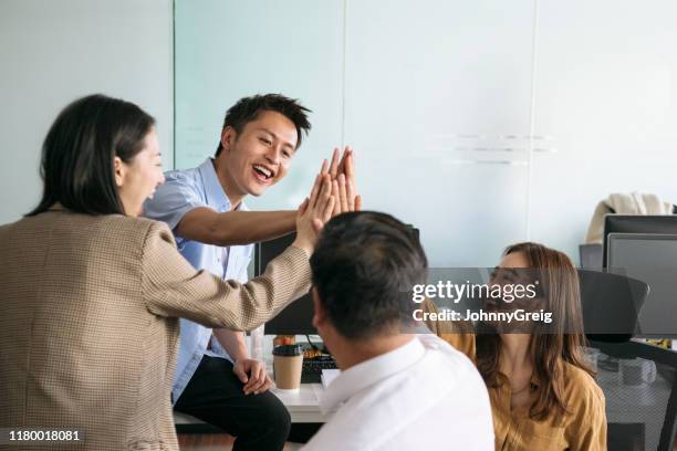 enérgicos colegas chinos celebrando el éxito empresarial - asia fotografías e imágenes de stock