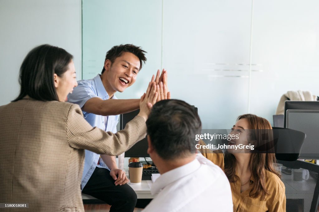 Energetic Chinese colleagues celebrating business success