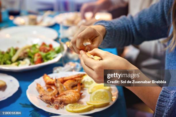 close-up of hands peeling prawns on the family table - mediterranean food fotografías e imágenes de stock