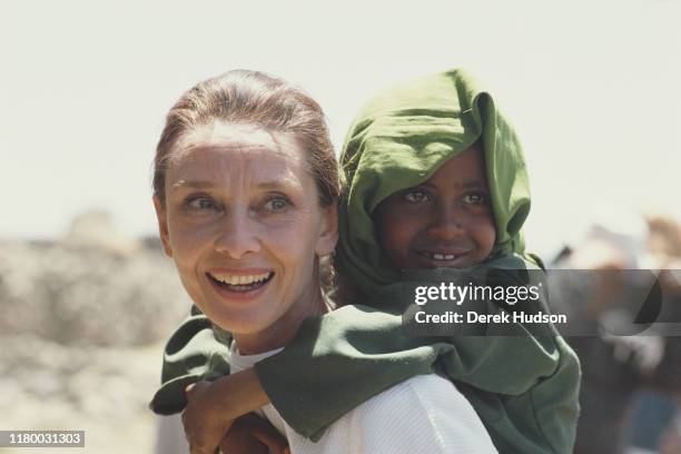 British actress and humanitarian Audrey Hepburn carrying an Ethiopian girl on her back while on her first field mission for UNICEF in Ethiopia,...