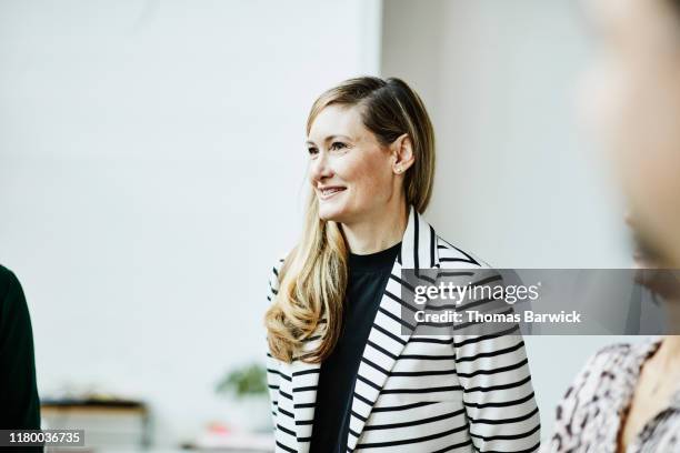 portrait of smiling businesswoman listening during meeting in office - striped jacket - fotografias e filmes do acervo