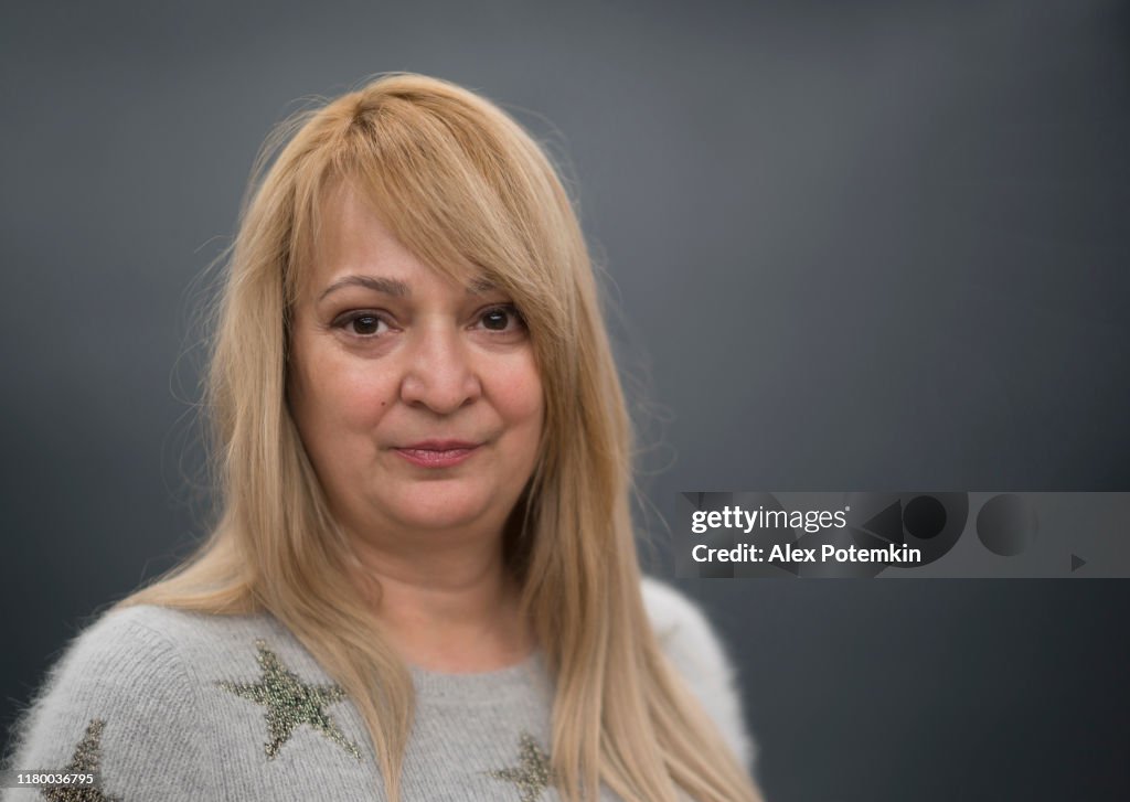 Portrait of the long-haired mature blonde woman against the gray background
