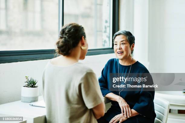 smiling senior businesswoman in discussion with client in office conference room - conversation fotografías e imágenes de stock