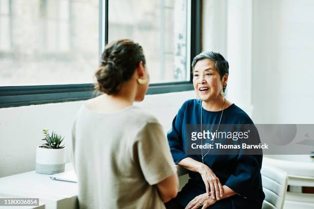 smiling senior businesswoman in discussion with client in office conference room - incoraggiamento foto e immagini stock