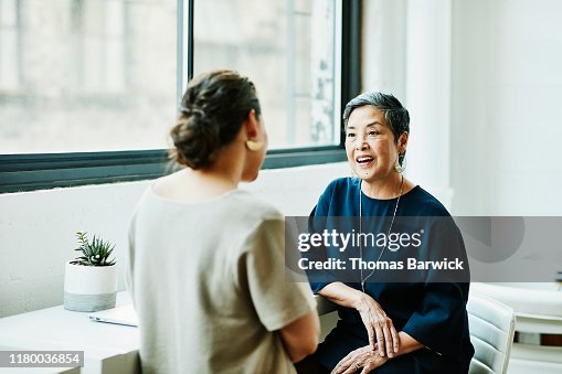 Smiling senior businesswoman in discussion with client in office conference room Smiling senior businesswoman in discussion with client in office conference room