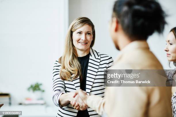 smiling businesswoman shaking hands with client before meeting - responsibility stock-fotos und bilder