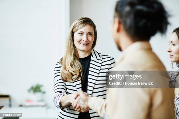smiling businesswoman shaking hands with client before meeting - satisfaction client photos et images de collection