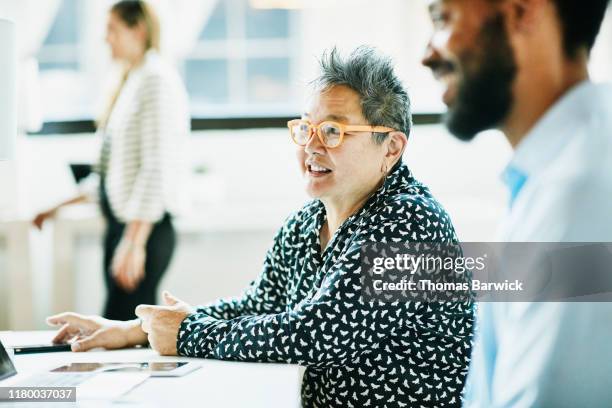 smiling senior businesswoman in discussion with colleague in coworking office - indian old man stockfoto's en -beelden