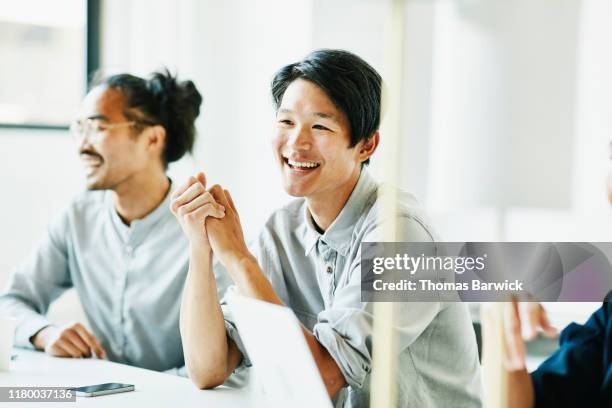 laughing businessman in discussion with colleagues during meeting in office conference room - asian young executive laughing office bildbanksfoton och bilder
