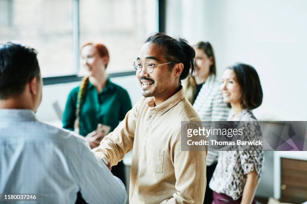 businessman shaking hands with colleague after meeting in office - multiracial group stock-fotos und bilder