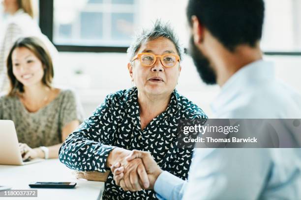 senior businesswoman shaking hands with client after meeting in office - businessman and businesswoman shaking hands stock pictures, royalty-free photos & images