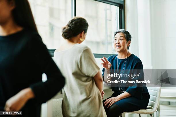 smiling senior businesswoman leading project discussion with colleague in office conference room - genius woman stock pictures, royalty-free photos & images