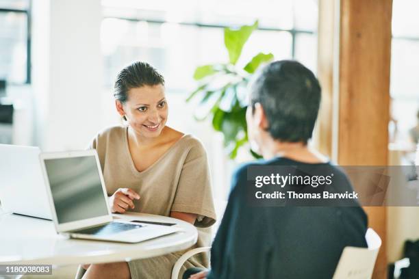 smiling businesswoman in discussion with client during meeting in office conference room - schwarzes haar stock-fotos und bilder