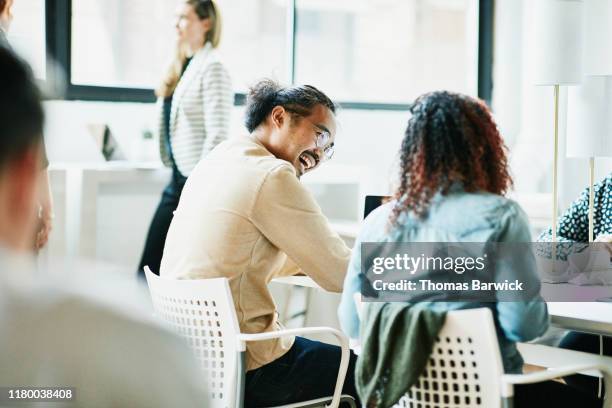 businessman laughing with colleague while working together in coworking space - fun at work stockfoto's en -beelden