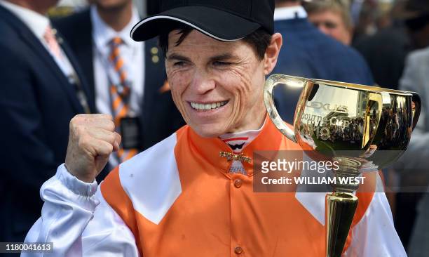 Jockey Craig Williams celebrates with the trophy after winning the Melbourne Cup horse race onboard Vow and Declare in Melbourne on November 5, 2019....