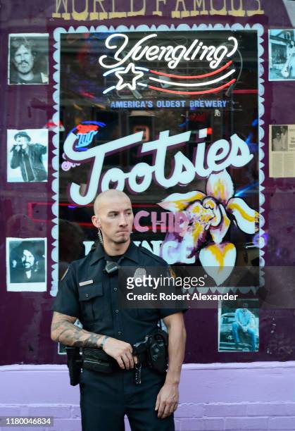 An armed private duty guard stands near the entrance to Tootsie's Orchid Lounge, an iconic bar and live country music venue in the Lower Broadway...