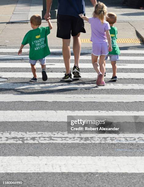 Man and his three young children cross a road at a pedestrian crosswalk in downtown Nashville, Tennessee.