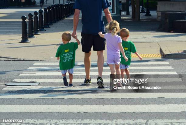 Man and his three young children cross a road at a pedestrian crosswalk in downtown Nashville, Tennessee.