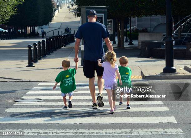 Man and his three young children cross a road at a pedestrian crosswalk in downtown Nashville, Tennessee.