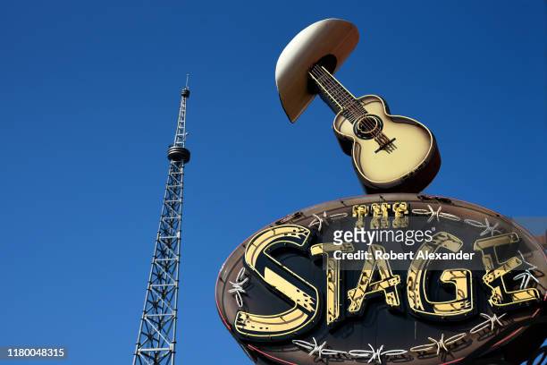 Neon sign above the entrance to The Stage bar and live music venue in Nashville, Tennessee, features a cowboy hat and a guitar. The tower is part of...