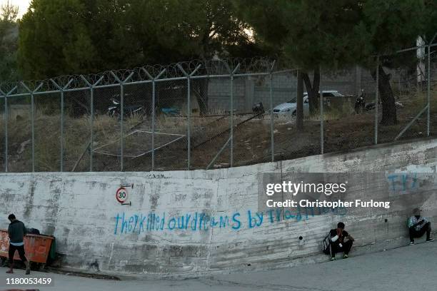 Men sit outside the Moria migrant camp which was built for 3,000 people but now contains over 13,000 on October 09, 2019 in Mytilene, Greece....