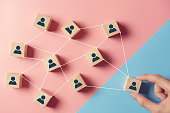 Building a strong team, Wooden blocks with people icon on pink and blue background, Human resources and management concept.