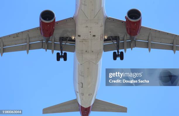lower view of a commercial jumbo jet aircraft in flight - landing gear stock-fotos und bilder