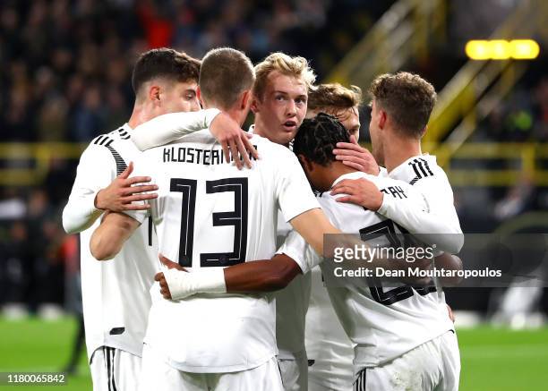 Serge Gnabry of Germany celebrates with team mates after he scores his sides first goal under pressure from Jonas Hector of Germany during the...