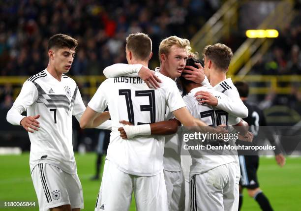 Serge Gnabry of Germany celebrates with team mates after he scores his sides first goal under pressure from Jonas Hector of Germany during the...