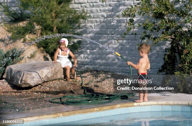 Young Todd Fisher plays with a hose with his sister Carrie Fisher by the pool at home in circa 1960.