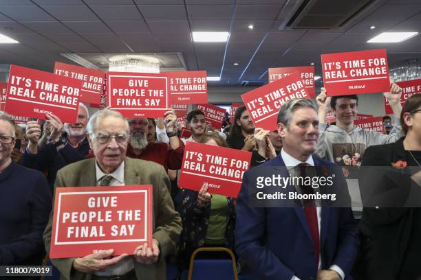 Attendees raise placards reading "It's time for real change" and "Give people the final say" as Jeremy Corbyn, leader of the Labour party, delivers a...