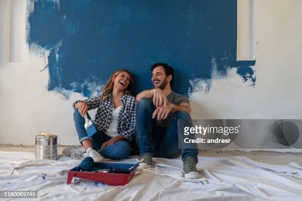 glückliches paar lacht, während er eine pause von der malerei - decoration stock-fotos und bilder