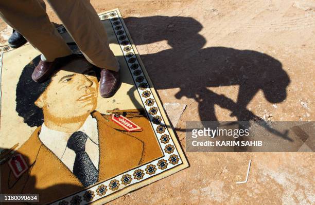 National Transitional Council fighter stands on a small rug with a portrait of Libya's ousted leader Moamer Kadhafi at the frontline in Bani Walid,...