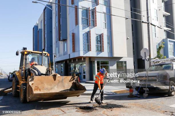 Contractor fills a hole in the street outside a newly completed housing redevelopment project at 1491 Sunnydale Avenue in San Francisco, California,...